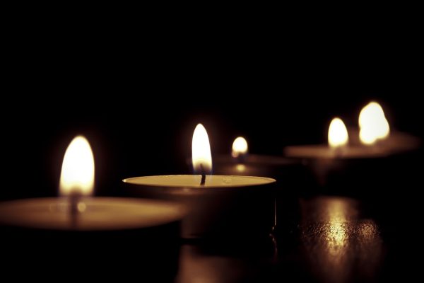 a few tea candles glow against a dark background