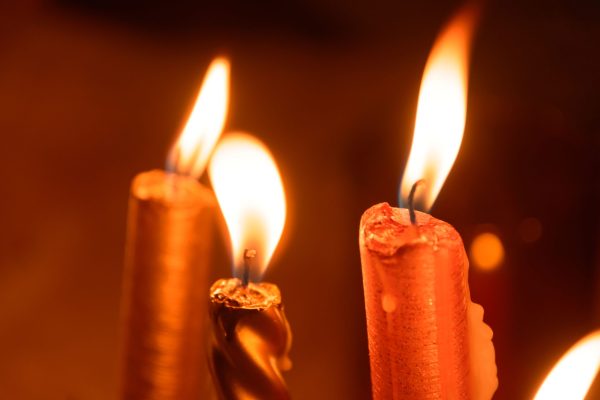 three candles glowing orange yellow in the dark