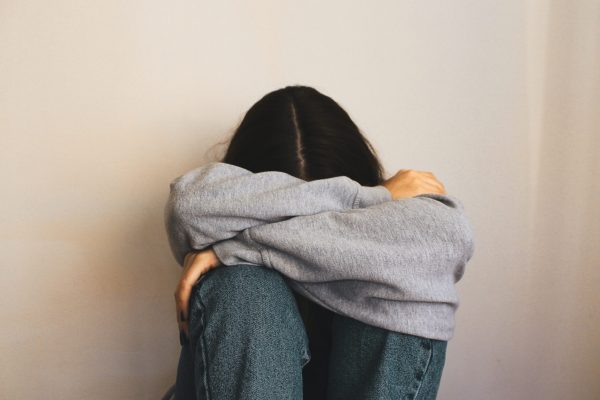 a woman sits with her head folded across her arms