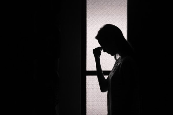 a person in shadow bent in grief