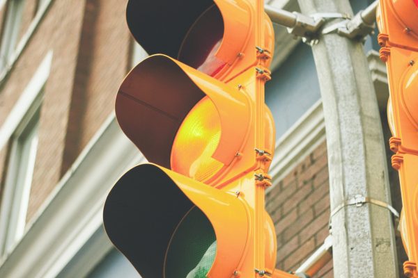 close up of traffic light at yellow in front of brick building
