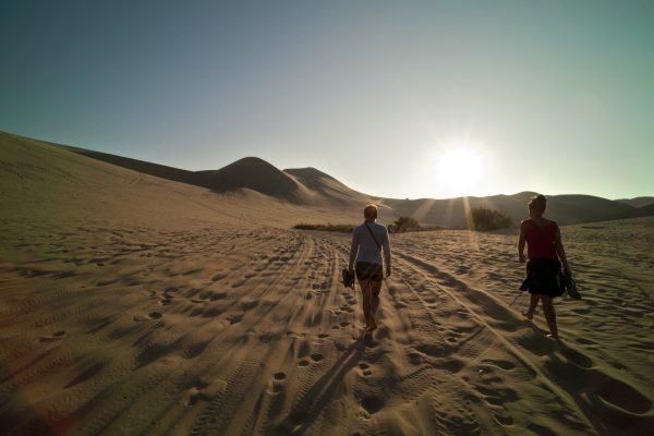 a person walkingthrough the desert, the sunset is ahead