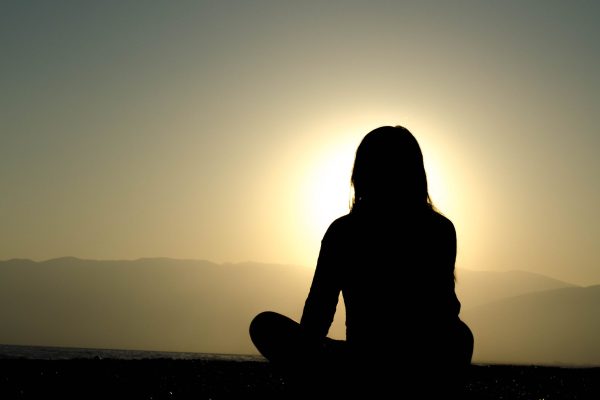 silhouette of person sitting before the sun