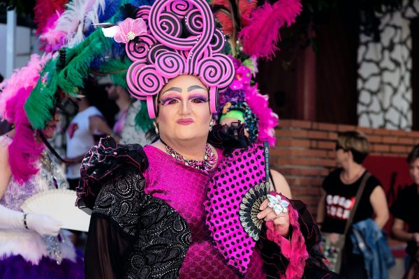 drag queen in pink headdress wearing a black and pink ruffled dress