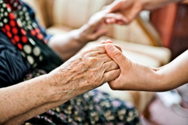 Close-up of two people holding hands, representing care and support.
