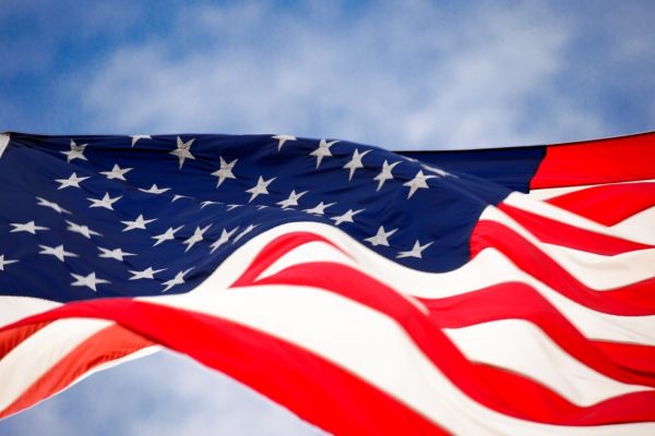 Close-up of a waving American flag against a blue sky.