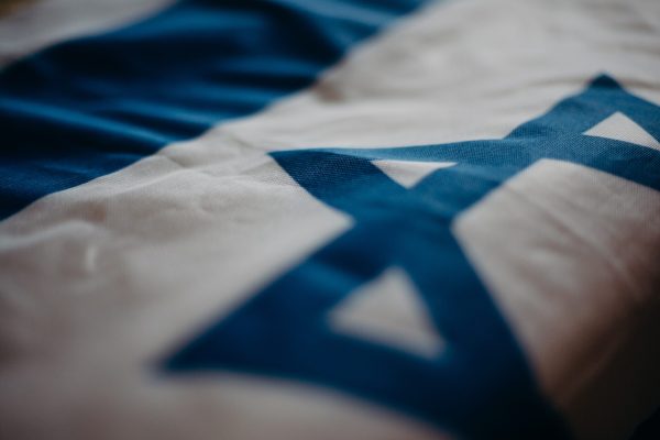 Close-up of a fabric displaying the Star of David in blue on a white background.