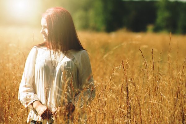 a young woman stands in a wheat field