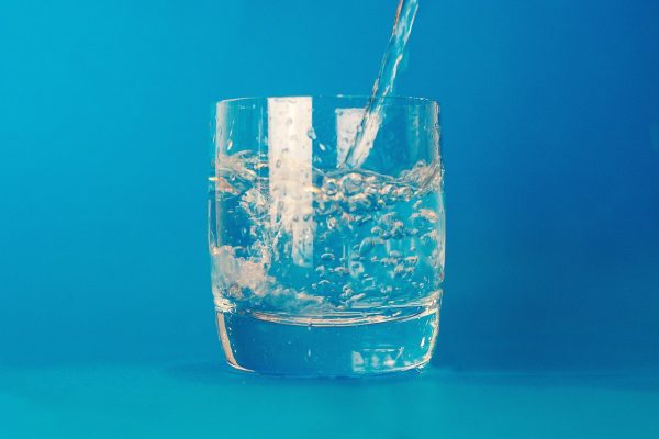 a stream of water is pouring into a short round glass