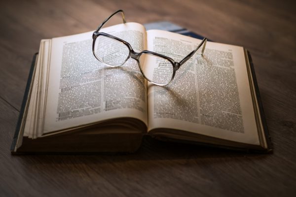 a pair of glasses sit on an open book