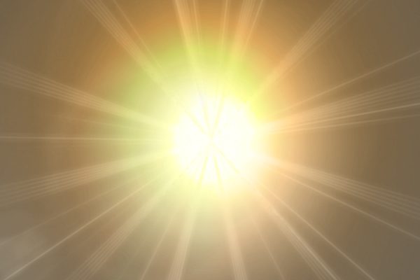 Bright yellow and orange sunburst with glowing rays radiating outward on a soft golden background.