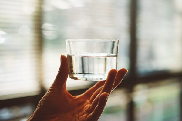 hand holding small glass of water