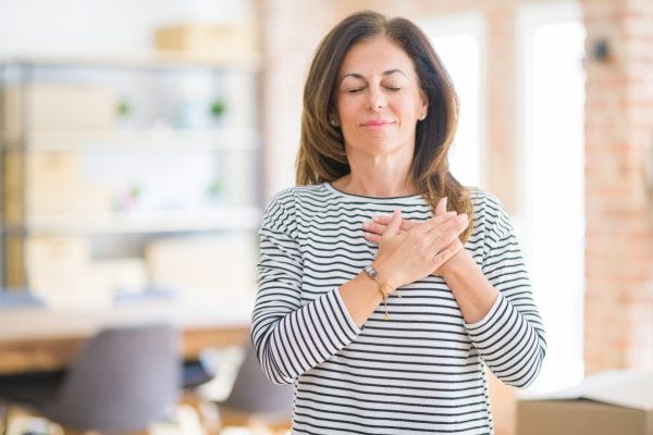 a woman places her hand on her heart