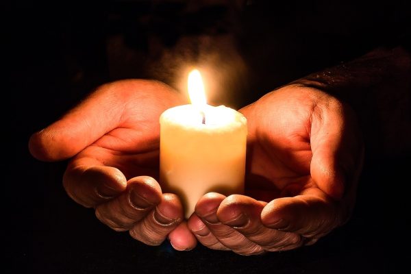 a person's hands are cupping a lit candle