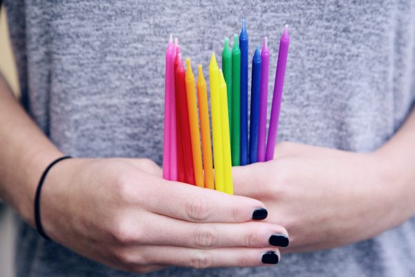 hands-with-black-nail-polish-holding-bright-colored-candles