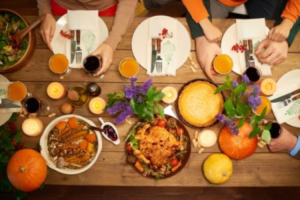 table with food and flowers and people's hands with empty plates