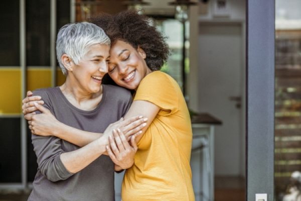 Two people hugging and smiling warmly in a cozy indoor setting.