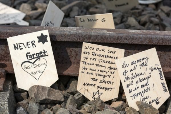 Memorial messages on wooden plaques among rocks, with a focus on remembering and honoring victims.