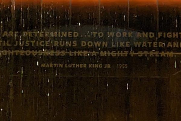 A wall with a water feature and a Martin Luther King Jr. quote about justice, partly obscured by falling water.