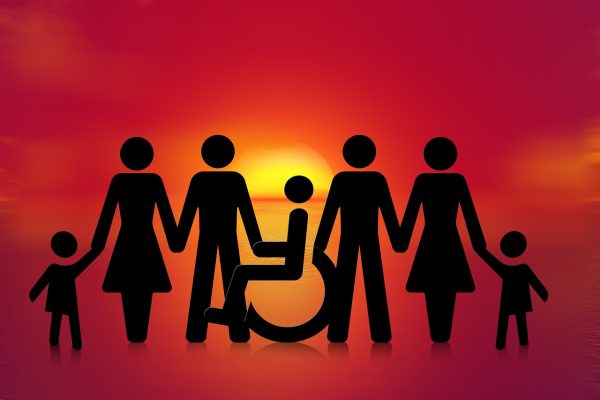 a silhouette of people holding hands including someone in a wheelchair