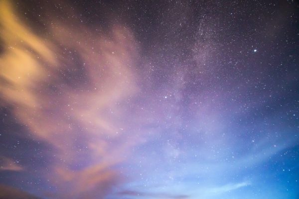 night sky with sweeping purple yellow blue clouds and stars in the background