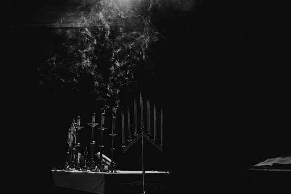 Black and white image of smoke rising from extinguished candles on a dimly lit table.