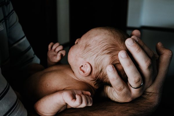closeup of newborn white baby held by adult white hands