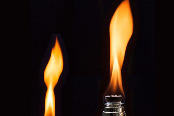 Close-up of a lighter with a tall, bright flame against a black background.