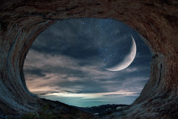 a crescent moon and stars seen through the lens of a cave