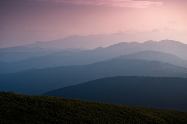 Soft, pink-lit mountain range with layered hills and a gentle gradient sky at dawn or dusk.
