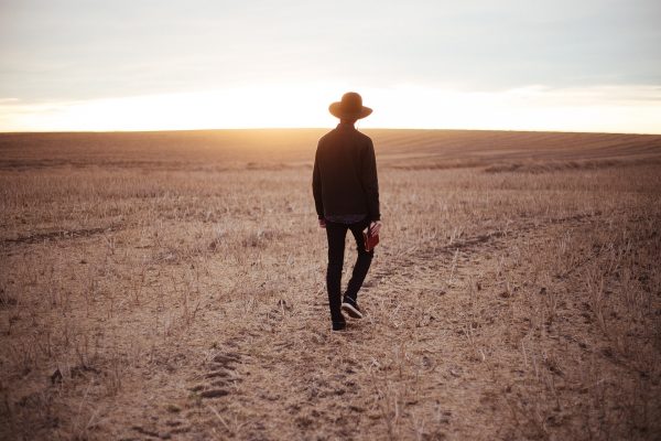 a person wearing a hat is walking through a field