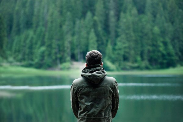 man facing water and forest