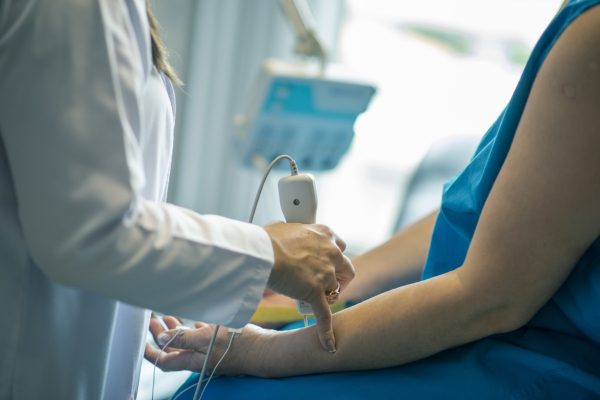 Healthcare professional performing an ultrasound on a patients arm in a medical setting.