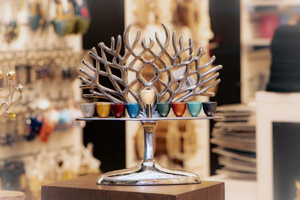 A silver menorah with colorful candle holders on display in a store.
