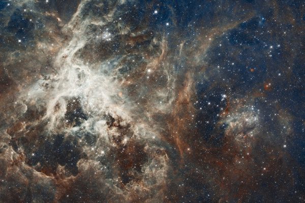 Stellar nebula with swirling clouds of gas and dust, illuminated by bright stars against a dark space background.