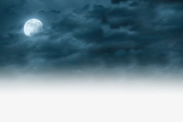 Full moon shining through clouds against a dark, misty sky.
