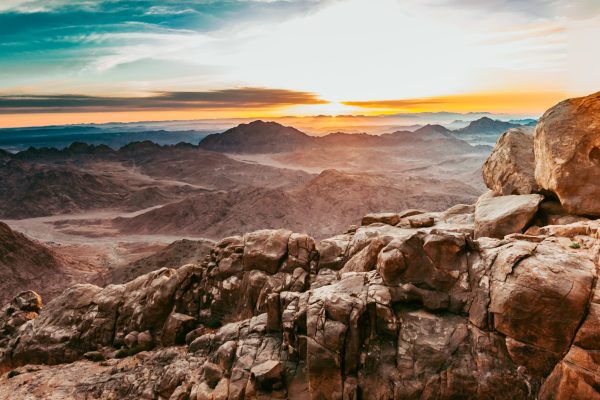Mt. Sinai, a rocky mountain landscape at sunrise with a dramatic sky and distant peaks.