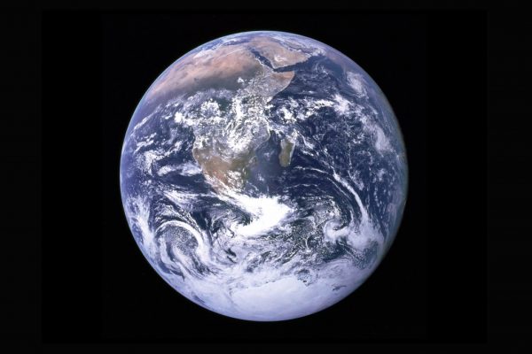 View of Earth from space, showing swirling clouds over continents and oceans against a black background.