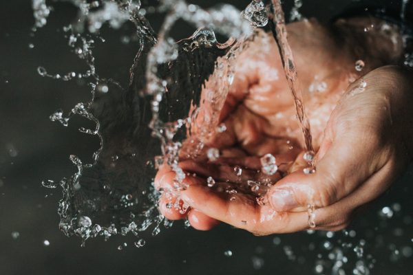 close up of cupped white hands under flowing water
