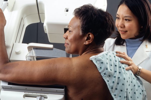 A medical professional assists a patient during a mammogram examination.