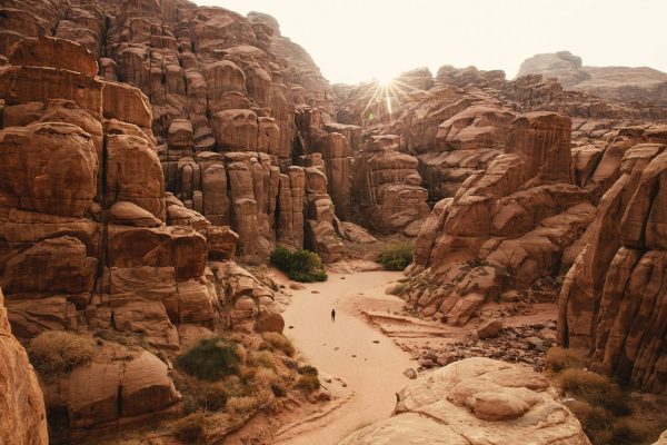 a person can be seen on a path surrounded by desert rock