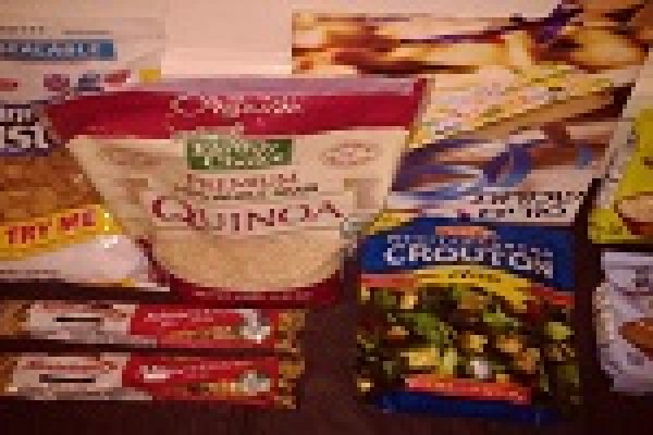 Assorted grocery items on a table, including quinoa, granola bars, cereals, and croutons.