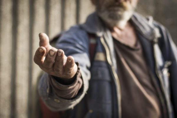 A person with an outstretched hand, wearing a denim jacket, appears to be asking for help.