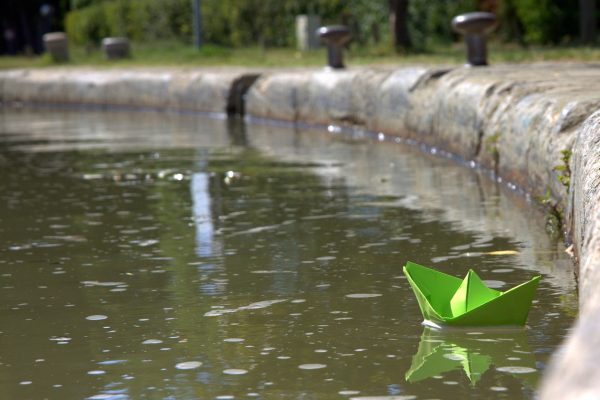 a paper boat sails on a pond