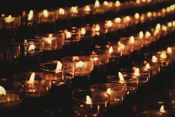 rows of lit candles shining in the ddark