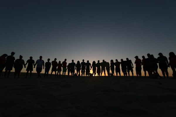a group of people standing in shadow, holding hands