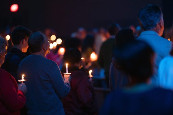 people holding lit candles at night