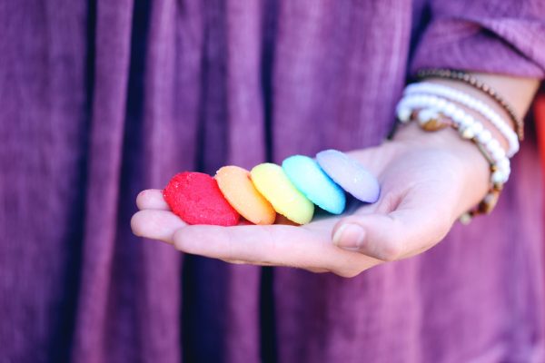 person in purple shirt holding rainbow cookies