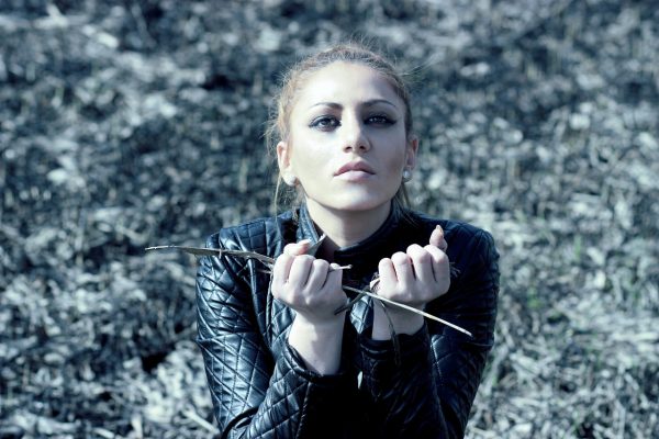 a woman in a devastated field crouched down and holding her hands in fists