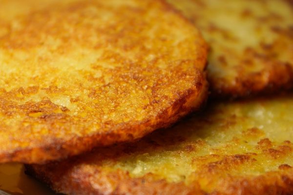 Close-up of golden, crispy potato pancakes stacked on a plate.